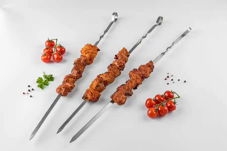 Schweine-Schaschlik Tomate auf Spiessen dekoriert mit Cocktail-Tomaten, Petersilie und bunten Pfefferkörnern.